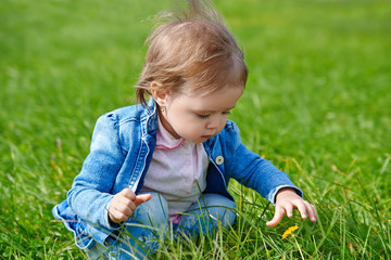 Baby girl crawling on the green grass outdoors in summer