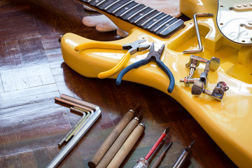 yellow electric guitar on wood in repair & luthier workshop, fixing & musical instrument repairing concept