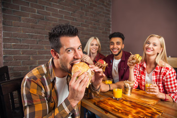 Wall Mural - People Group Eating Fast Food Burgers Sitting At Wooden Table In Cafe