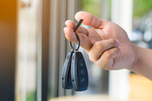 A hand holding car keys and a remote control for key entry