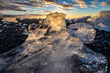 Wall Mural - Sunrise shot through a gigantic iceberg on black sand beach, Iceland. Iceland Tourist attraction.