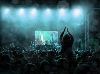 Rock concert, silhouettes of happy people raising up hands