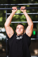 Wall Mural - Young man doing pull ups on horizontal bar outdoors, workout, sport concept