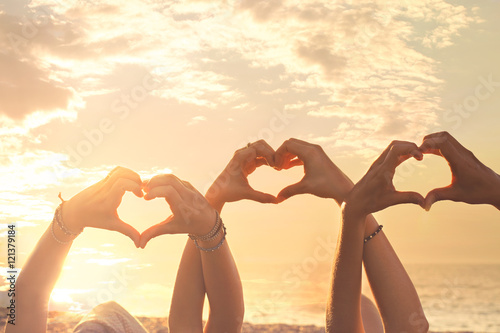 Fotografía three hands of a heart-shaped woman hurled into the sky at sunse