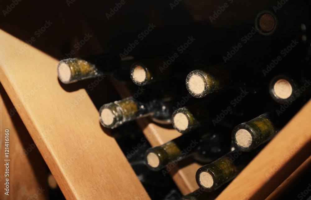 Bottles with wine on wooden shelves in cellar