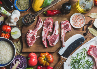 Wall Mural - Ingredients for cooking dinner. Raw uncooked lamb meat ribs, rice, oil, spices and vegetables over wooden background, top view, horizontal composition