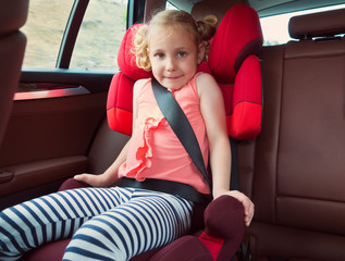 Wall Mural - Portrait of happy little child girl sitting comfortable in car s