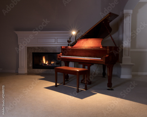 Fotografija  Grand Piano with reading light and glowing fireplace during even