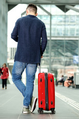 Man standing in airport with travel bag