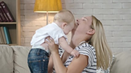 young mother tossing her toddler son up and down and then hugging and kissing him