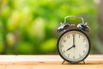 clock on wood table in the green garden time at 8 o'clock