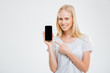 © Drobot Dean - Smiling young woman pointing finger at blank smartphone screen