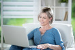 © jackfrog - a retired woman sitting in a chair with a laptop at home