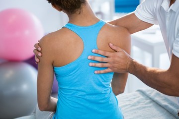 Physiotherapist giving back massage to female patient