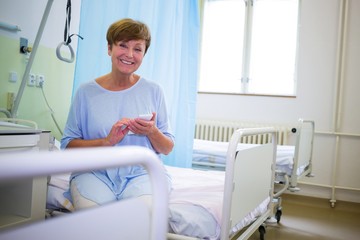 Wall Mural - Portrait of smiling senior patient using mobile phone 