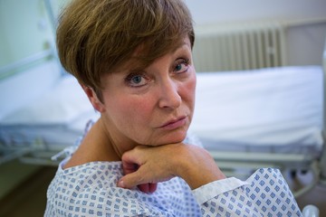 Wall Mural - Portrait of sad senior patient sitting on a bed