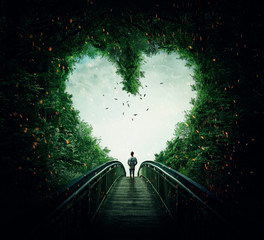 boy walking on a bridge through the heart shape woods, following the light. follow your heart concep