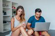 © jakubzak - Young couple is sitting on the bed while using pc laptop and mob