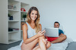 © jakubzak - Young couple is sitting on the bed while using pc laptop and mob