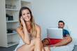 © jakubzak - Young couple is sitting on the bed while using pc laptop and mob