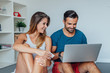 © jakubzak - Young couple is sitting on the bed and using laptop pc to online