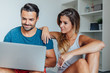© jakubzak - Young couple is sitting on the bed and using laptop pc to online