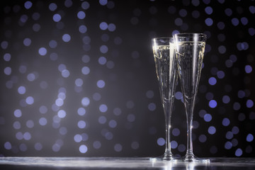 Two glasses of champagne on dark bokeh background