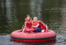 Cute Kids Having Fun Riding Bumper Boats On A Lake