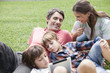 © PhotoAlto - Happy family enjoying in park while young boy using digital tablet