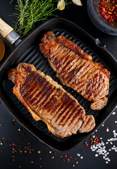 Wall Mural - Fresh cooked meat Beef Steak Sirloin for two. in iron grilled pan with herbs.