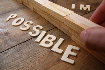 Poster - man hand building the wall between of the letters IM from the word impossible so it says possible.