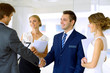 © volha_r - Businessmen shaking hands. Two confident businessmen shaking hands and smiling while standing at office together with people in the background