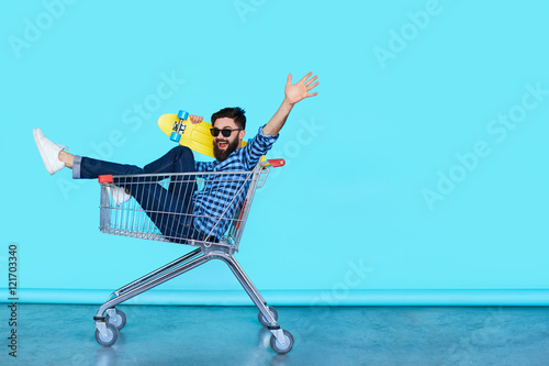 Fotografía Side view of cheerful young man sitting in shopping cart