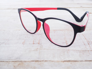 Black and red eye glasses on wood background