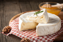 Brie Type Of Cheese. Camembert Cheese. Fresh Brie Cheese And A Slice On A Wooden Board With Nuts, Honey And Leaves. Italian, French Cheese.