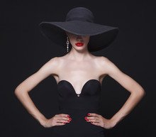 Luxury Woman In A Large Black Hat And Bright Lips On Black Background