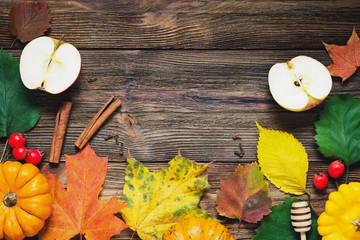 Autumn holiday card with fallen leaves, spices, pumpkins and food ingredients for cooking on wooden background. Copy space for text