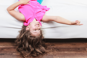 Wall Mural - Little girl kid with long hair upside down on sofa