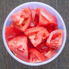 Wall Mural - Fresh red tomato slice in plastic box on white wood table background