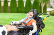 Disabled boy in wheelchair playing with soccer ball at park