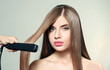 Woman smoothing long hair on light background