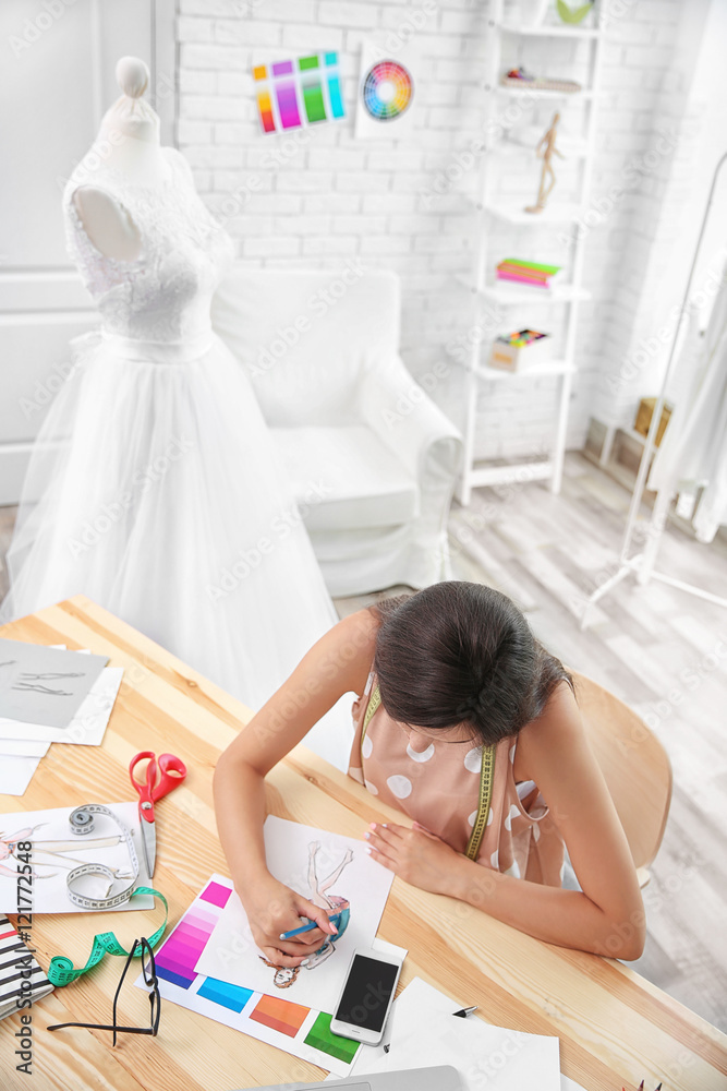 Pretty young dress designer at workplace