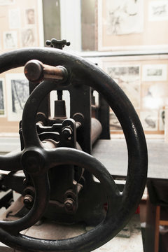 Grip of ancient handle printing press, close-up. Old iron printery equipment, spindle with rusty gears. Ancient publishing house instrument