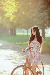 Wall Mural - The young girl with bicycle in park