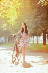 Wall Mural - The young girl with bicycle in park