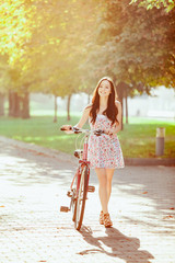 Wall Mural - The young girl with bicycle in park