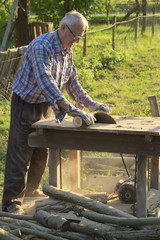 Older man cutting woods with circular saw