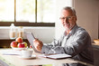 © zinkevych - Portrait of happy senior man using laptop in kitchen at home