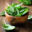 Spinach leaves in wooden bowl against dark rustic background