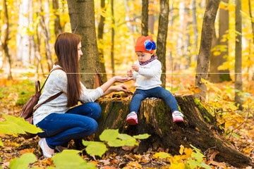 Mother and little daughter playing together in autumn park